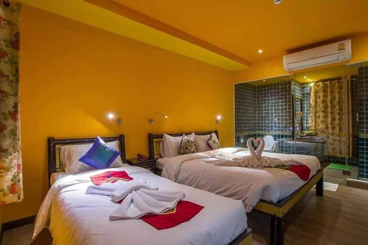 A hotel room with two beds, a mirror, and an air conditioning unit on the wall.