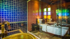 Habitación de hotel con cama, separador de vidrio y puerta corrediza.