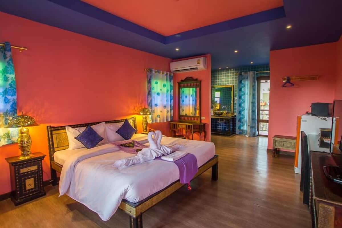 A hotel room with a bed, bedside tables, an air conditioning unit, a desk, and a chair.