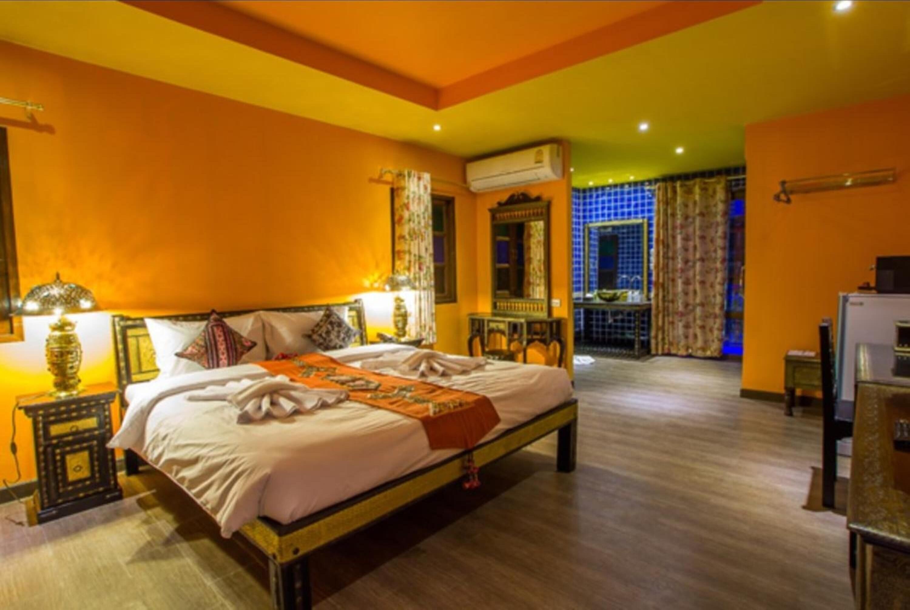 Ein Hotelzimmer mit einem großen Bett, einem Nachttisch mit Lampe, einem kleinen Tisch und einem Fernseher.