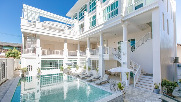 A multi-story building with a swimming pool, outdoor seating, and a staircase. - De Hug Hotel & Residence (Chiang Rai)
