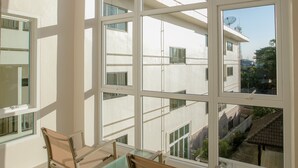 A room with large windows, a table, and two chairs. - De Hug Hotel & Residence (Chiang Rai)