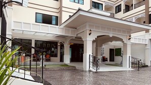 A spacious courtyard with a stone floor, white pillars, and a covered entrance area. - De Hug Hotel & Residence (Chiang Rai)