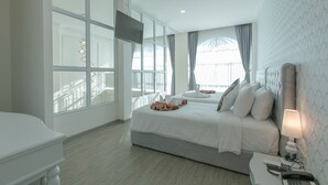 A modern hotel room with a large bed, a bedside table with a lamp, and a TV mounted on the wall. - De Hug Hotel & Residence (Chiang Rai)