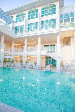 A multi-level hotel with a central pool area, multiple balconies, and a staircase connecting the floors.