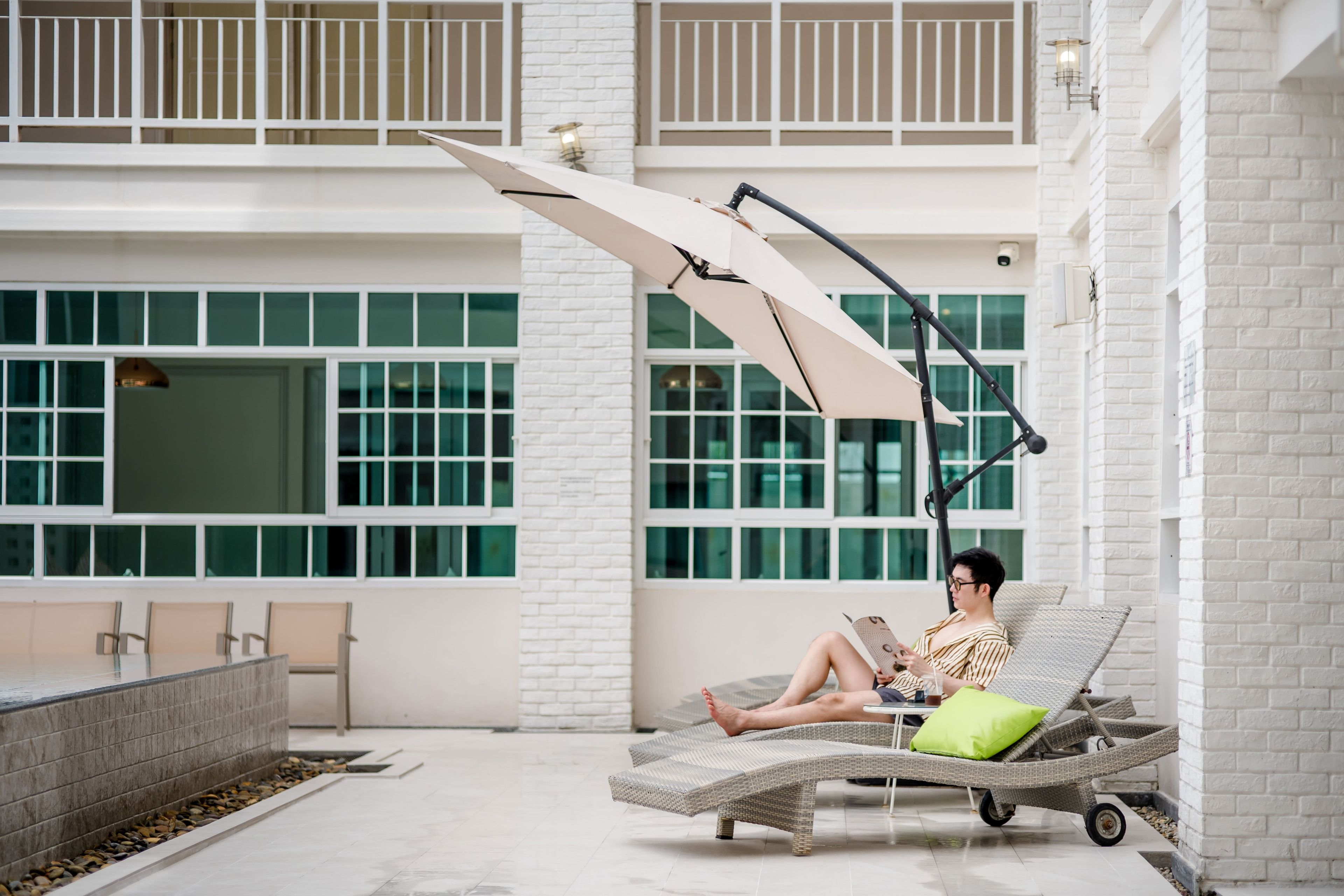 Un área de descanso con una silla reclinable, una mesa y una sombrilla grande que proporciona sombra.