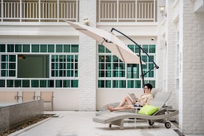 Un área de descanso con una silla reclinable, una mesa y una sombrilla grande que proporciona sombra.