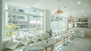 A modern hotel room with large windows, a marble table, and a seating area with white cushions. - De Hug Hotel & Residence (Chiang Rai)