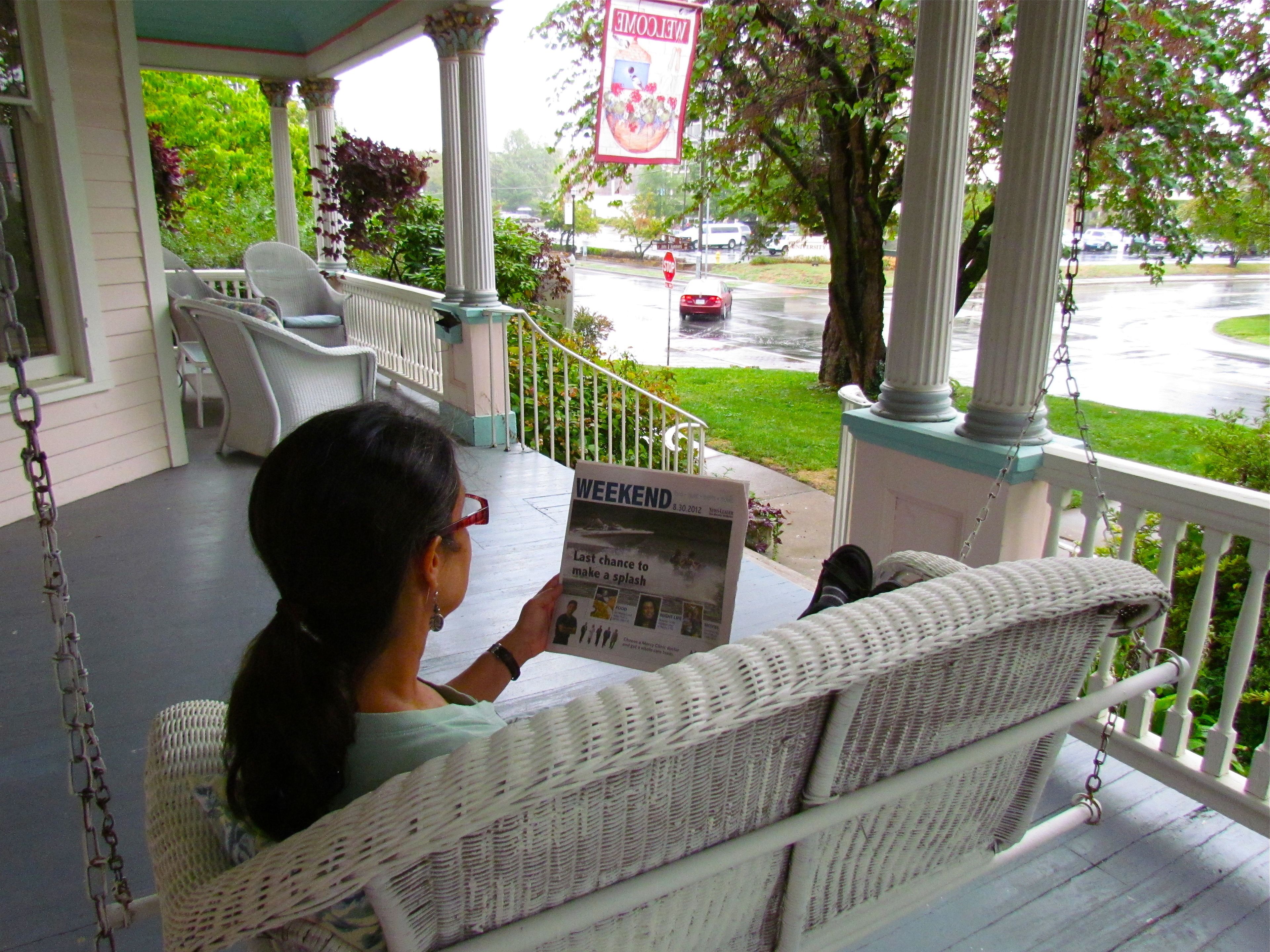 A porch with wicker furniture and a newspaper.