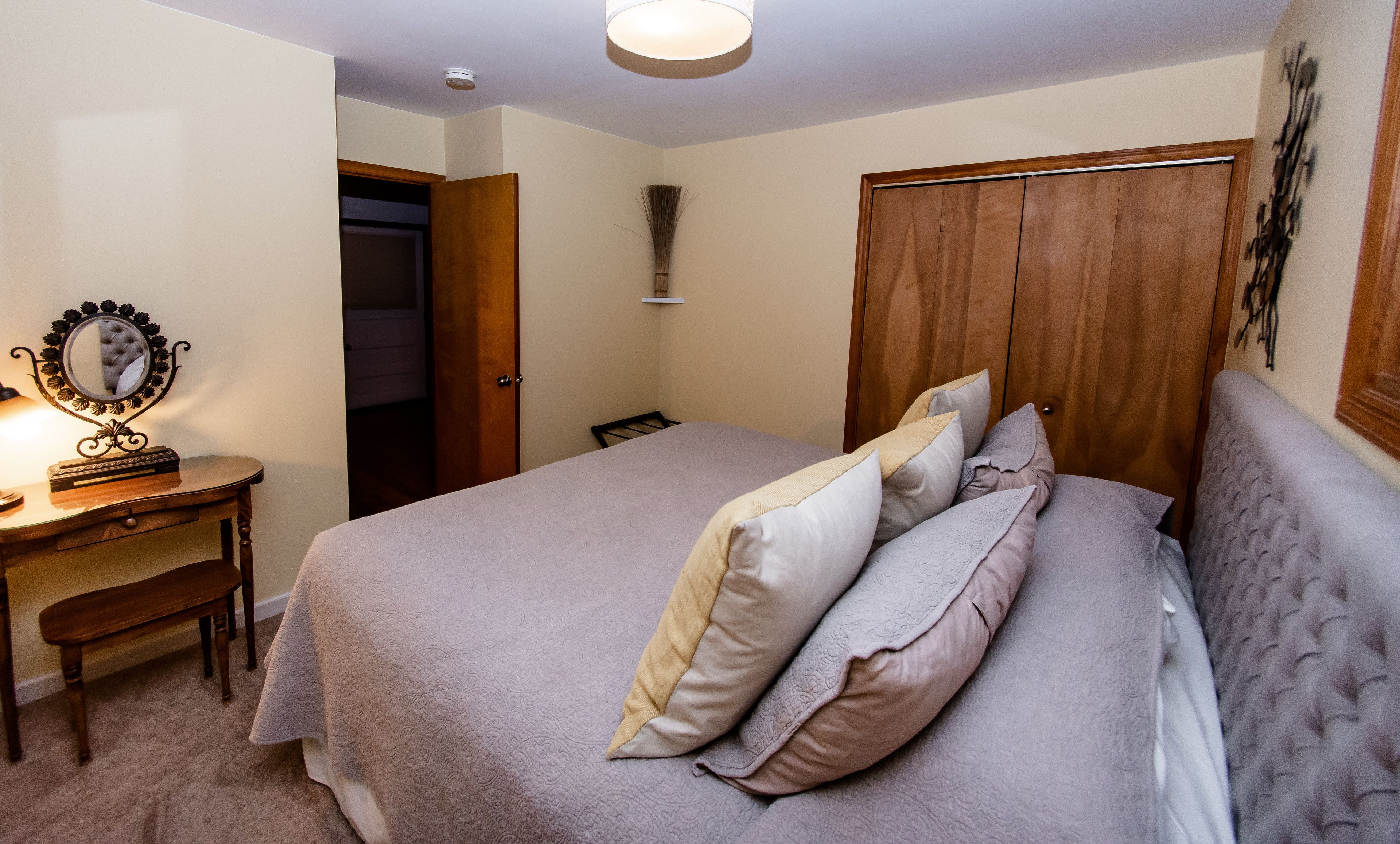 A bedroom with a bed, bedside table, mirror, and wardrobe.