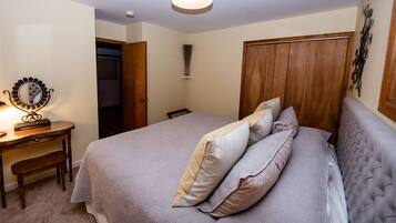A bedroom with a bed, bedside table, mirror, and wardrobe.