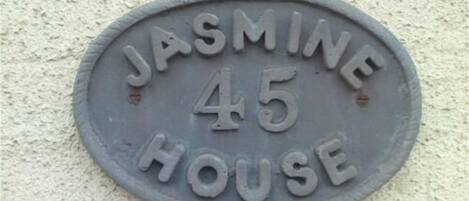 A house number plaque reading "JASMINE 45 HOUSE" on a textured wall.
