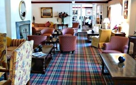 A cozy living room with patterned sofas, a plaid carpet, and a fireplace.