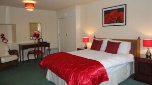 Habitación de hotel con una cama grande, dos lámparas de noche, un escritorio con una silla, un espejo y un cuadro en la pared.
