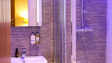 A modern bathroom with a glass-enclosed shower, a white sink, and a mirror above it.