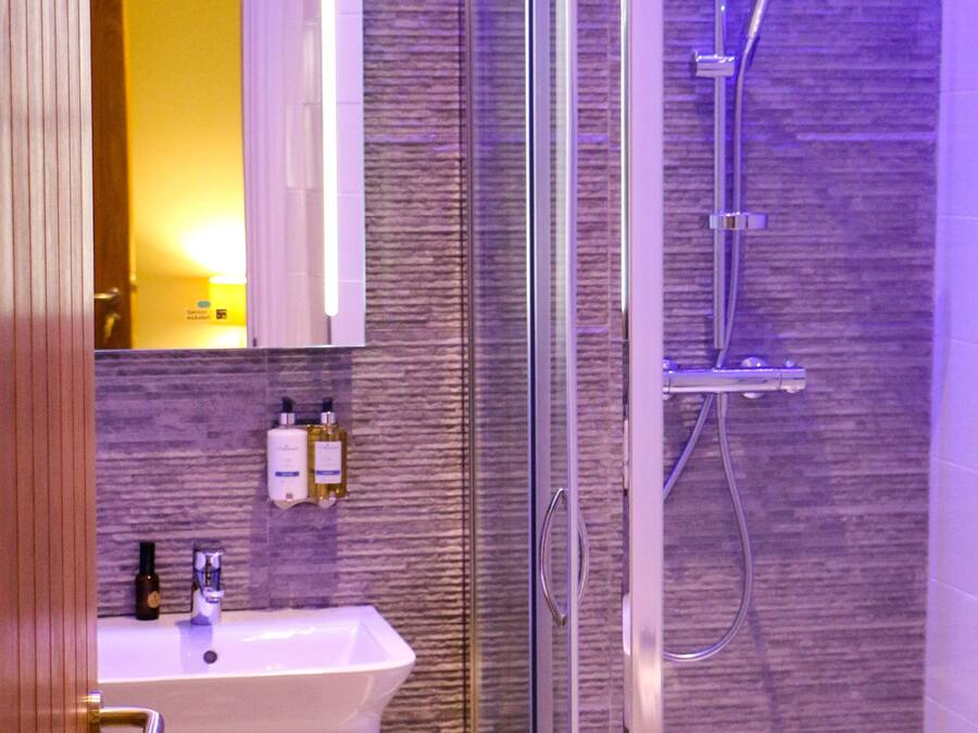 A modern bathroom with a glass-enclosed shower, a white sink, and a mirror above it.