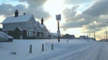 A snow-covered road with a building on the left.