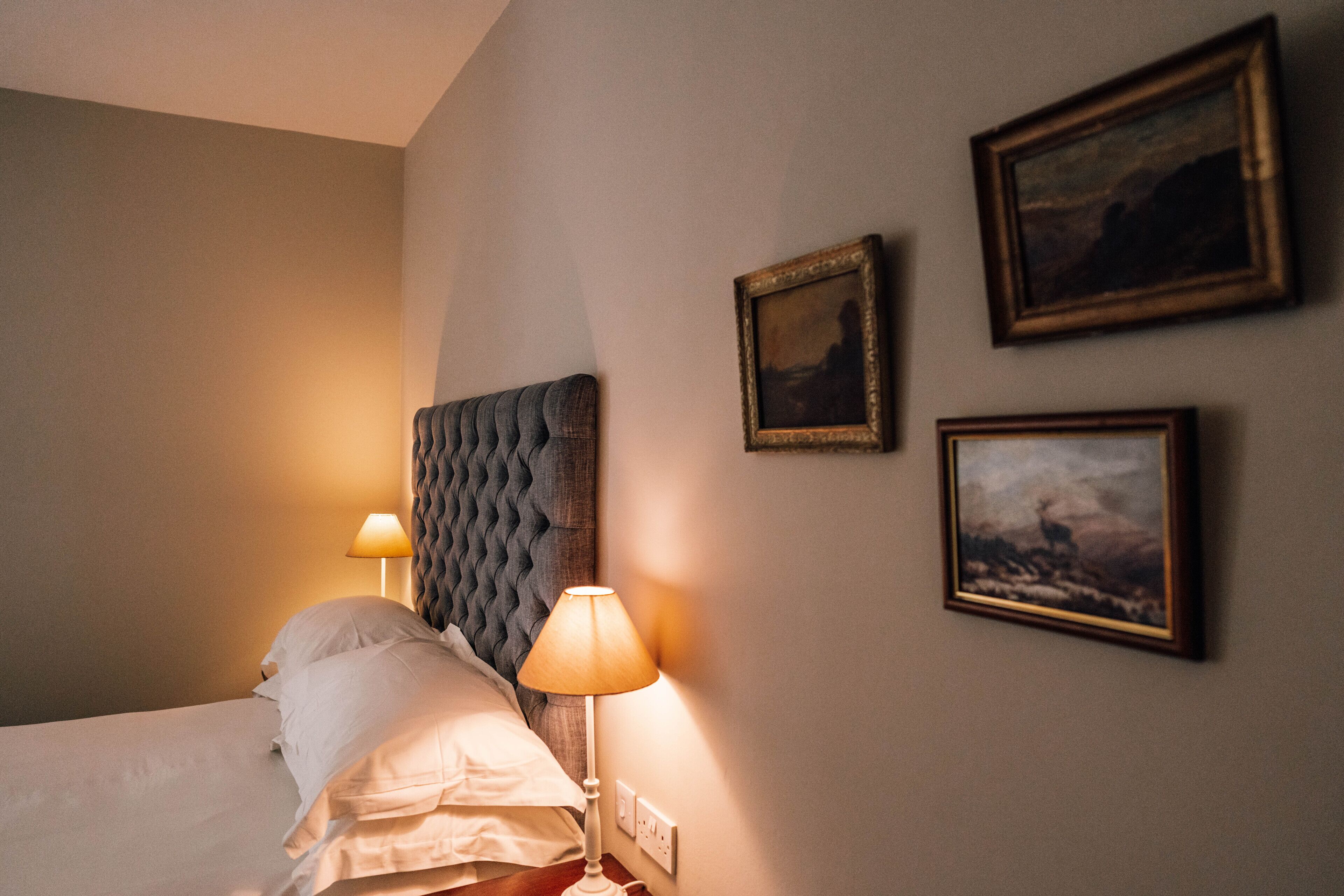 Et hotelværelse med en seng, to sengeborde og tre billeder hængende på væggen.