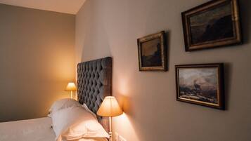 Una habitación de hotel con una cama, dos lámparas de noche y tres cuadros en la pared.