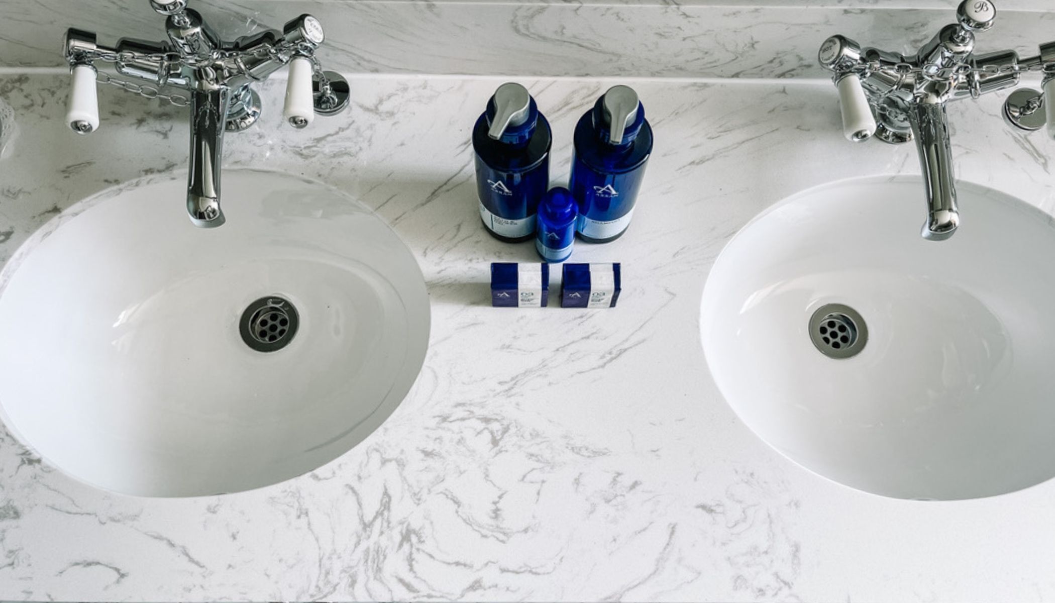 A bathroom with two white sinks and a marble countertop.