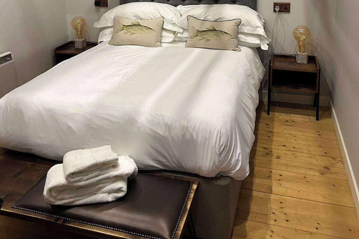 A bedroom with a large bed, a headboard, bedside tables, and a wooden floor.