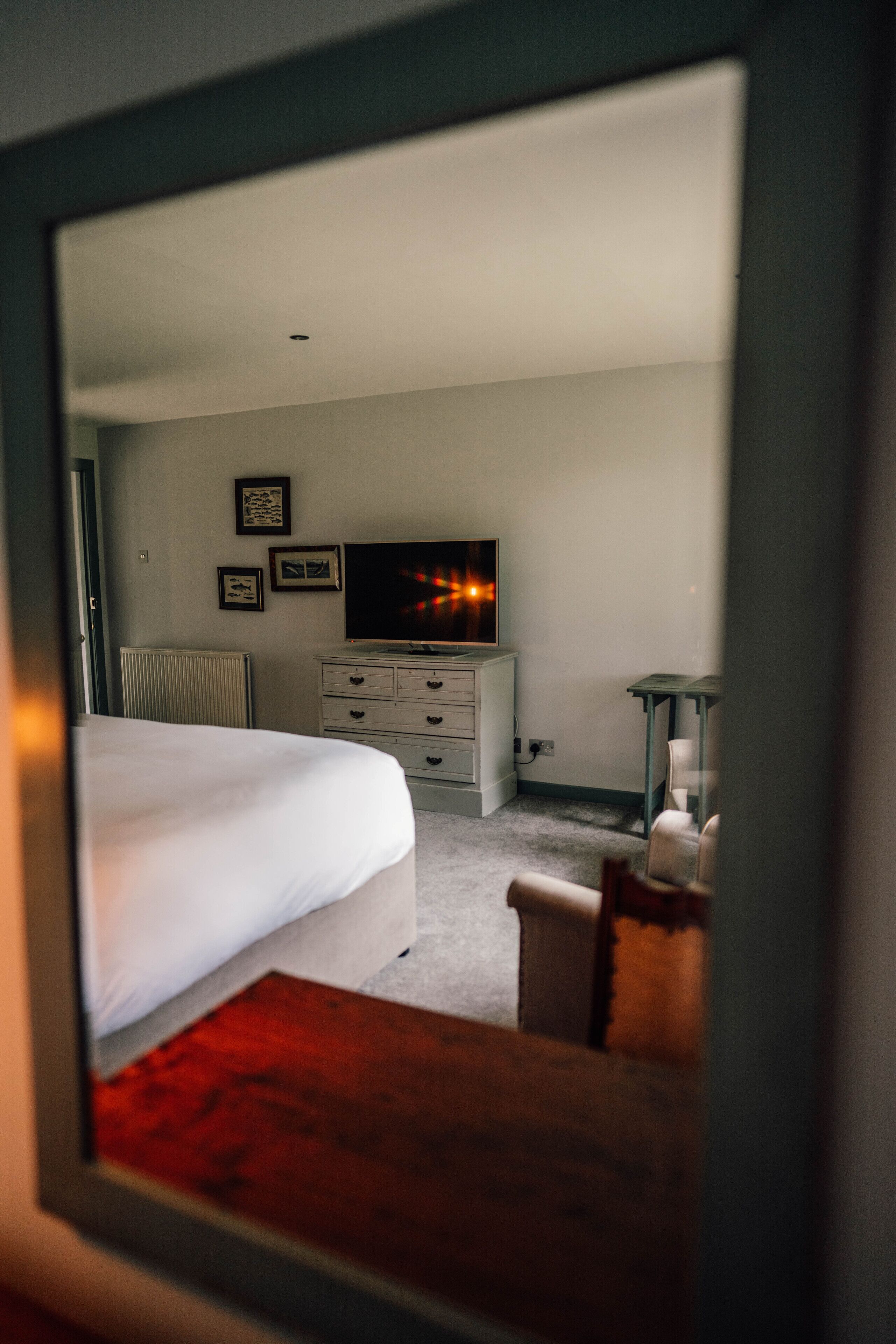 A bedroom with a bed, dresser, TV, and framed pictures on the wall.