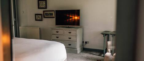 A bedroom with a bed, dresser, TV, and framed pictures on the wall.
