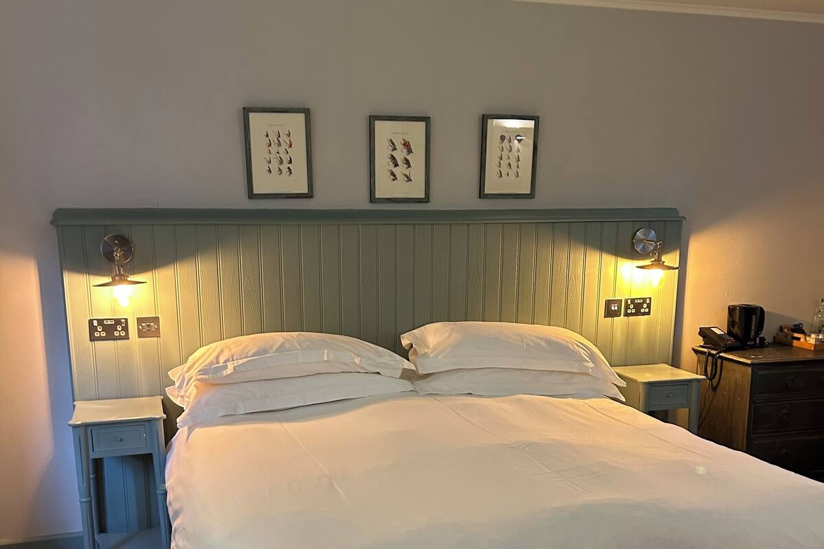 A double bed with a wooden headboard, two bedside tables with lamps, and three framed pictures on the wall.