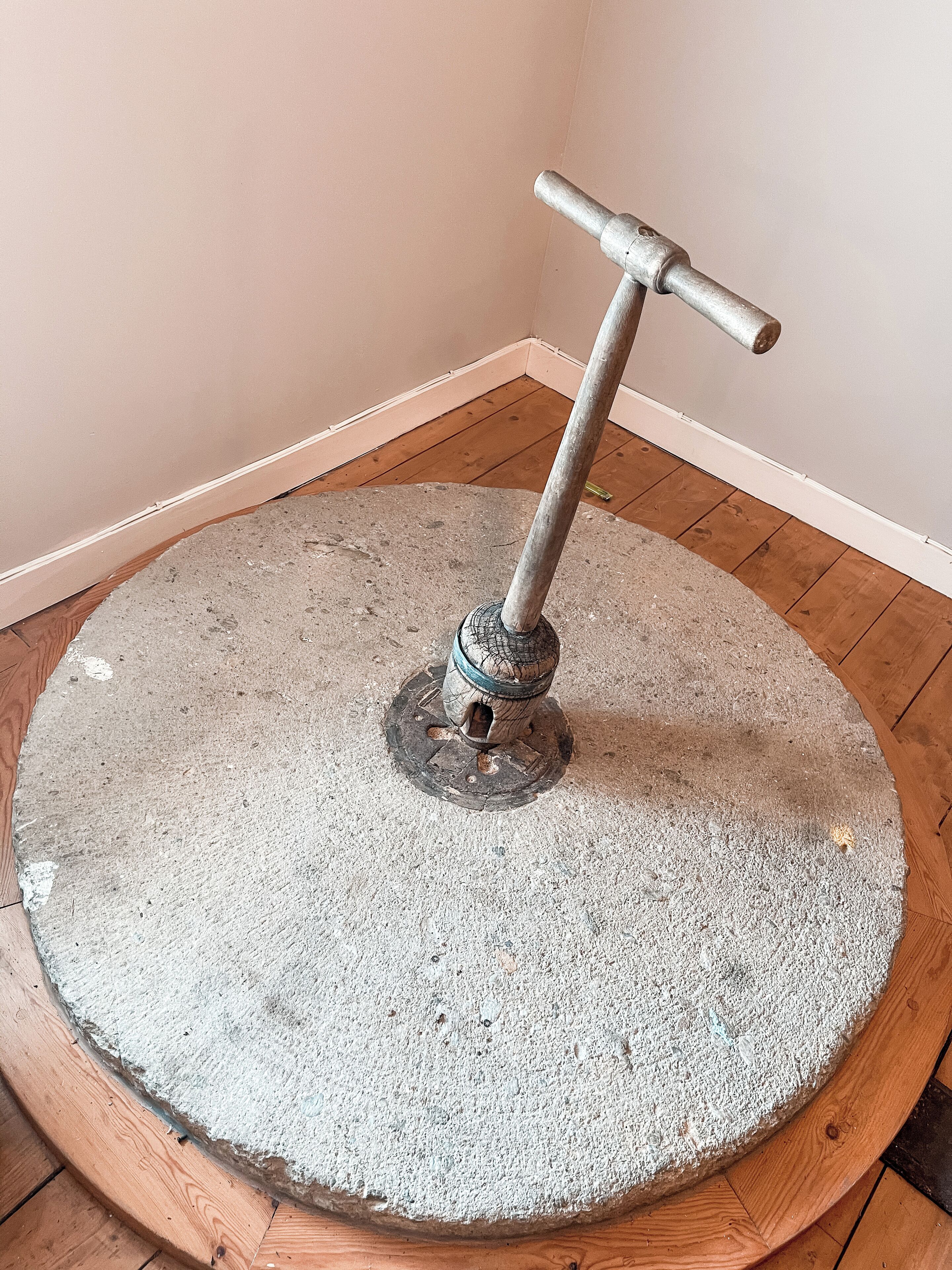 Una mesa redonda de piedra con un soporte metálico y un asa.
