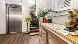 Un interior moderno con una escalera, una estatua decorativa y un ascensor.