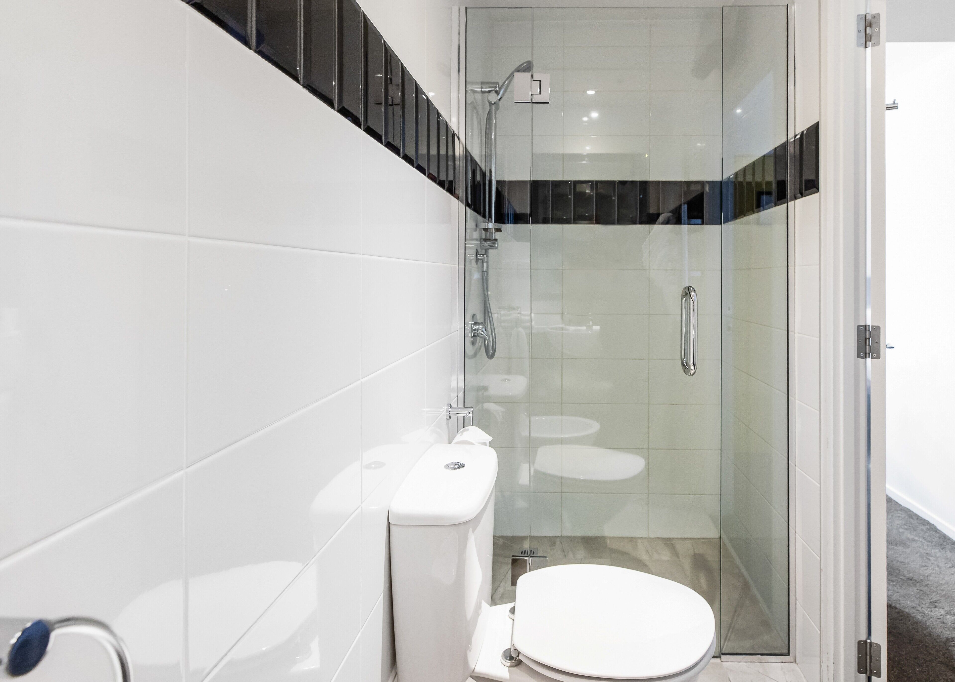 A modern bathroom with a glass-enclosed shower, a toilet, and a sink.