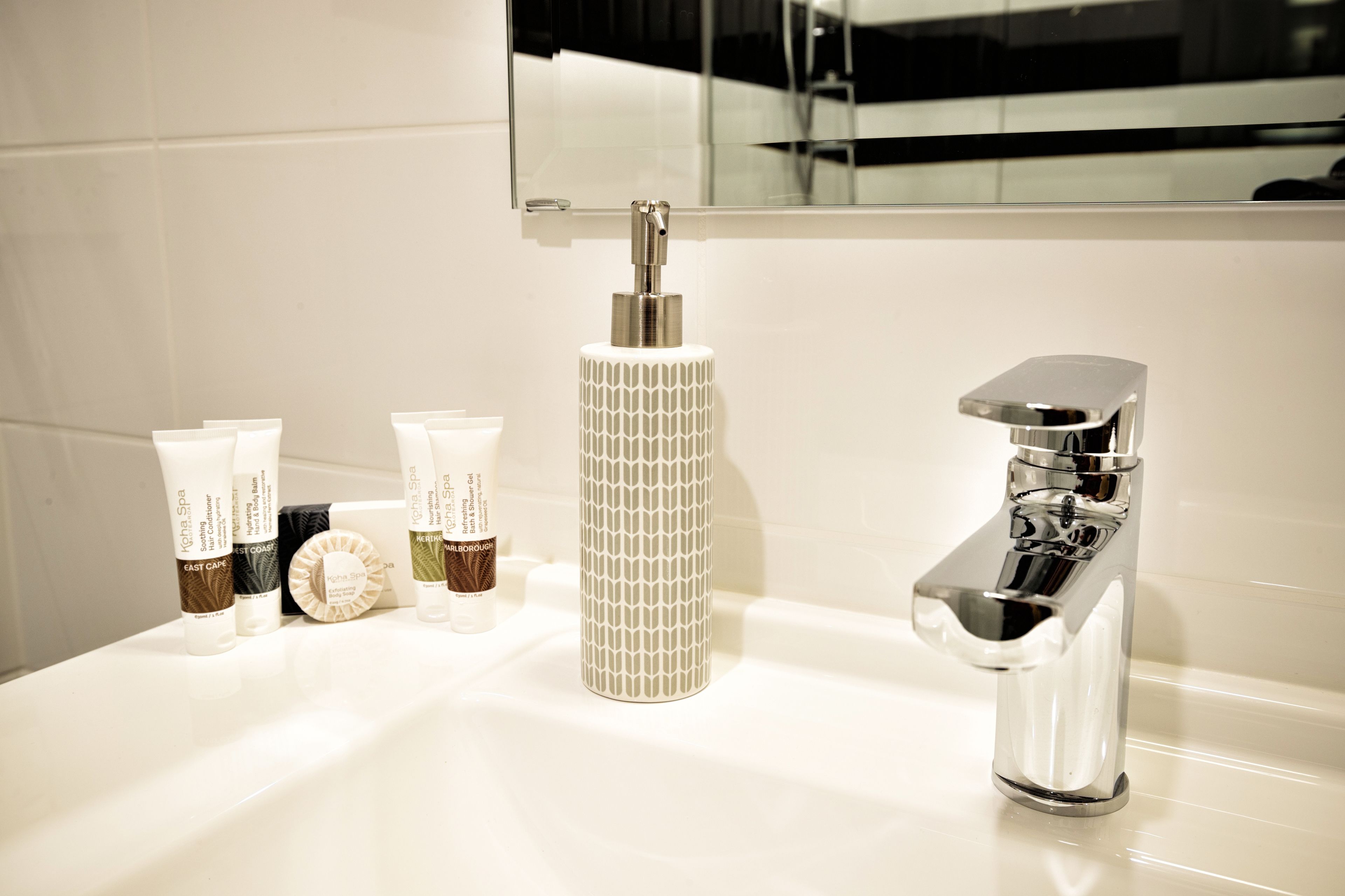A bathroom with a white sink, a chrome faucet, and a mirror above the sink.