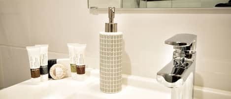 Une salle de bain avec un lavabo blanc, un robinet chromé et un miroir au-dessus du lavabo.