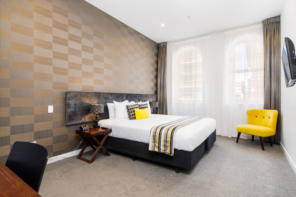 Une chambre d’hôtel moderne, dotée d’un grand lit, d’un bureau et d’une chaise.