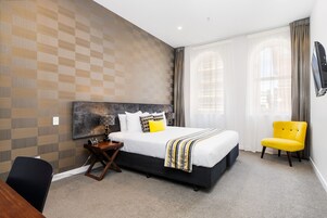 Una habitación de hotel moderna con una cama grande, un escritorio y una silla.