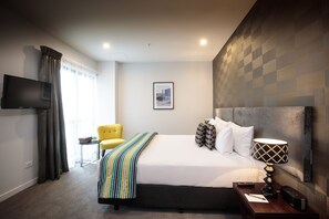 Relax in comfort with a neatly made bed, a bedside table, and a TV for entertainment.