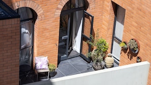 Edificio de ladrillo con ventanas de arco y un balcón con macetas.