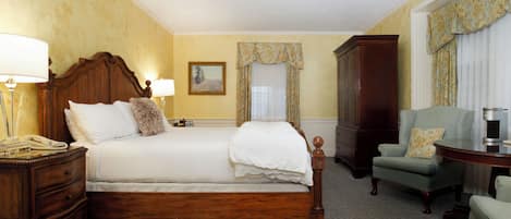 A hotel room with a large bed, a wooden nightstand, a chair, a cabinet, and a window with curtains.