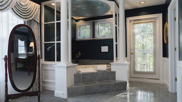 A bathroom with a bathtub, a mirror, and a window.