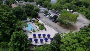 An aerial view of a hotel with a swimming pool, outdoor seating, and a parking lot.
