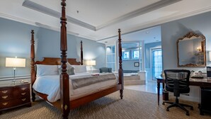 A spacious bedroom with a four-poster bed, a desk, and a chair.