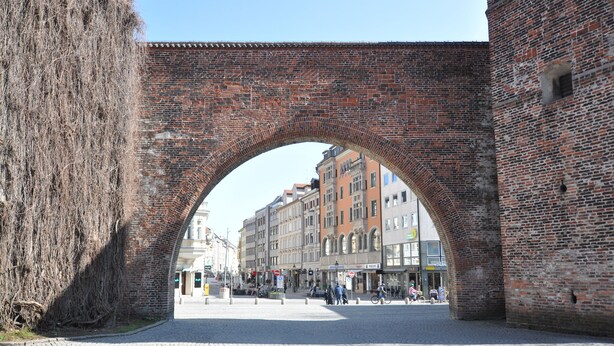 An arched brick bridge in a city square with buildings in the background. - Hotel Altmünchen (Munich)