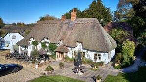 A traditional thatched-roof building with a patio area, outdoor seating, and a garden.