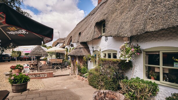 A traditional building with thatched roofs, outdoor seating, and potted plants.