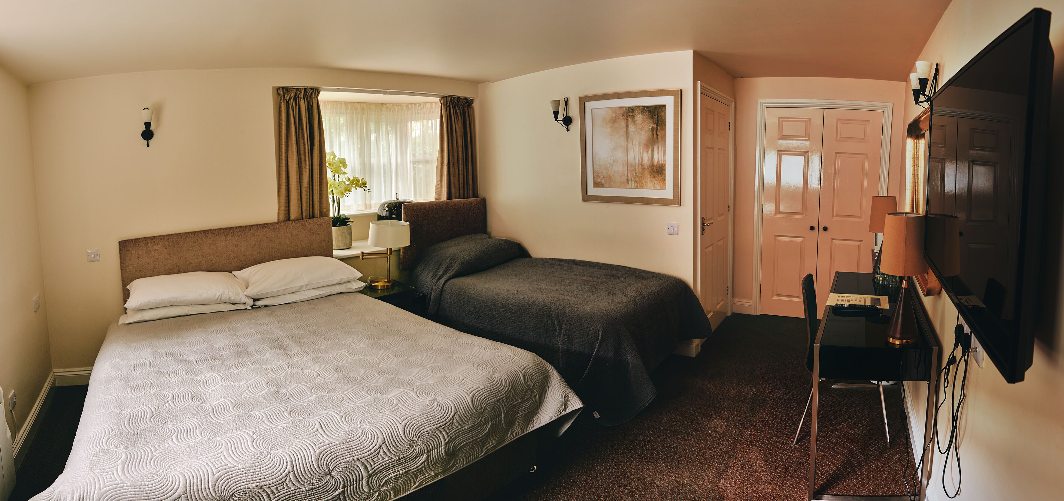 Habitación de hotel con dos camas, un escritorio, una silla, un televisor y una ventana con cortinas.