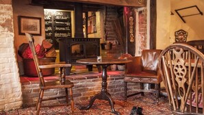 A cozy room with a patterned carpet, wooden furniture, and a fireplace.