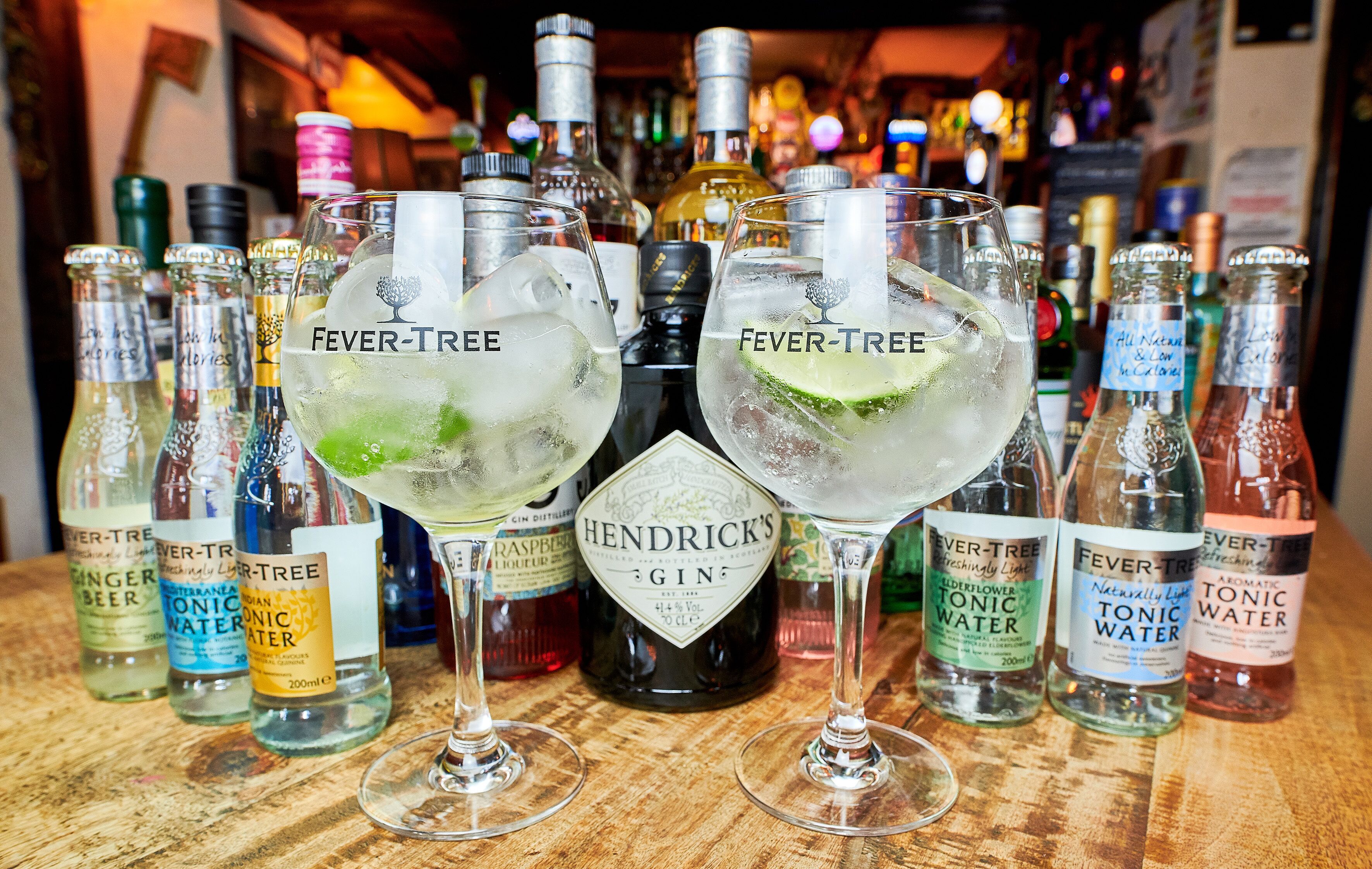 Un bar avec différents types de bouteilles et de verres, notamment des produits de la marque « Fever-Tree » et du gin « Hendrick’s ».