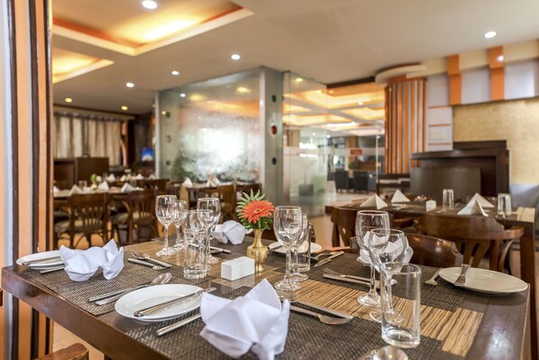 A restaurant setting with tables set for dining, including plates, cutlery, and glasses. - Airport Hotel Kathmandu - Near Pashupatinath Temple (Kathmandu)