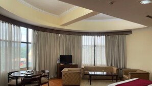Una camera d'albergo con un letto, una poltrona, una televisione, un tavolo da pranzo con sedie e un tavolino con una sedia.