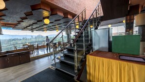 Un ristorante con una scala che conduce a una terrazza, un bancone in legno e vista sulle montagne.